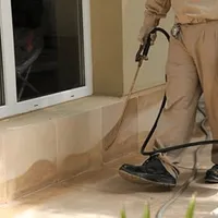General pest control technician spraying exterior perimeter around a home in Boca Raton, FL