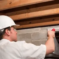 Termite inspection technician checking a basement wall and framing for termite activity in Boca Raton, FL